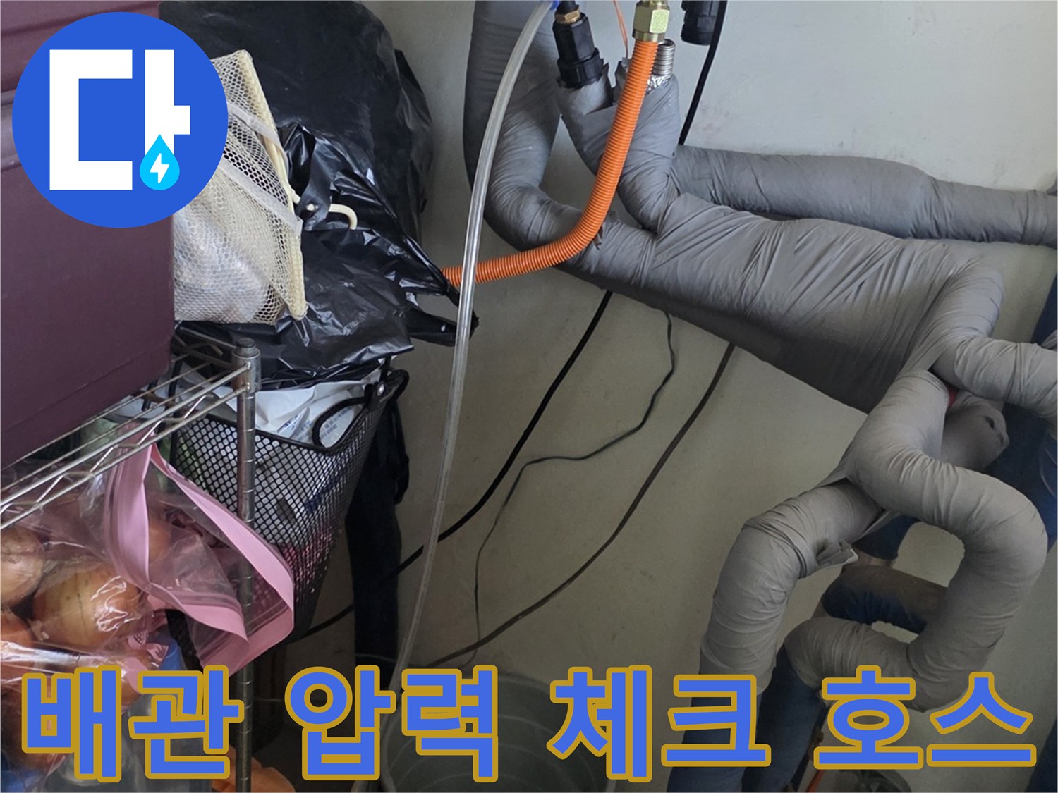 보일러 하단 배관에 연결된 주황색 압력 테스트용 호스 - 누수 진단 작업
