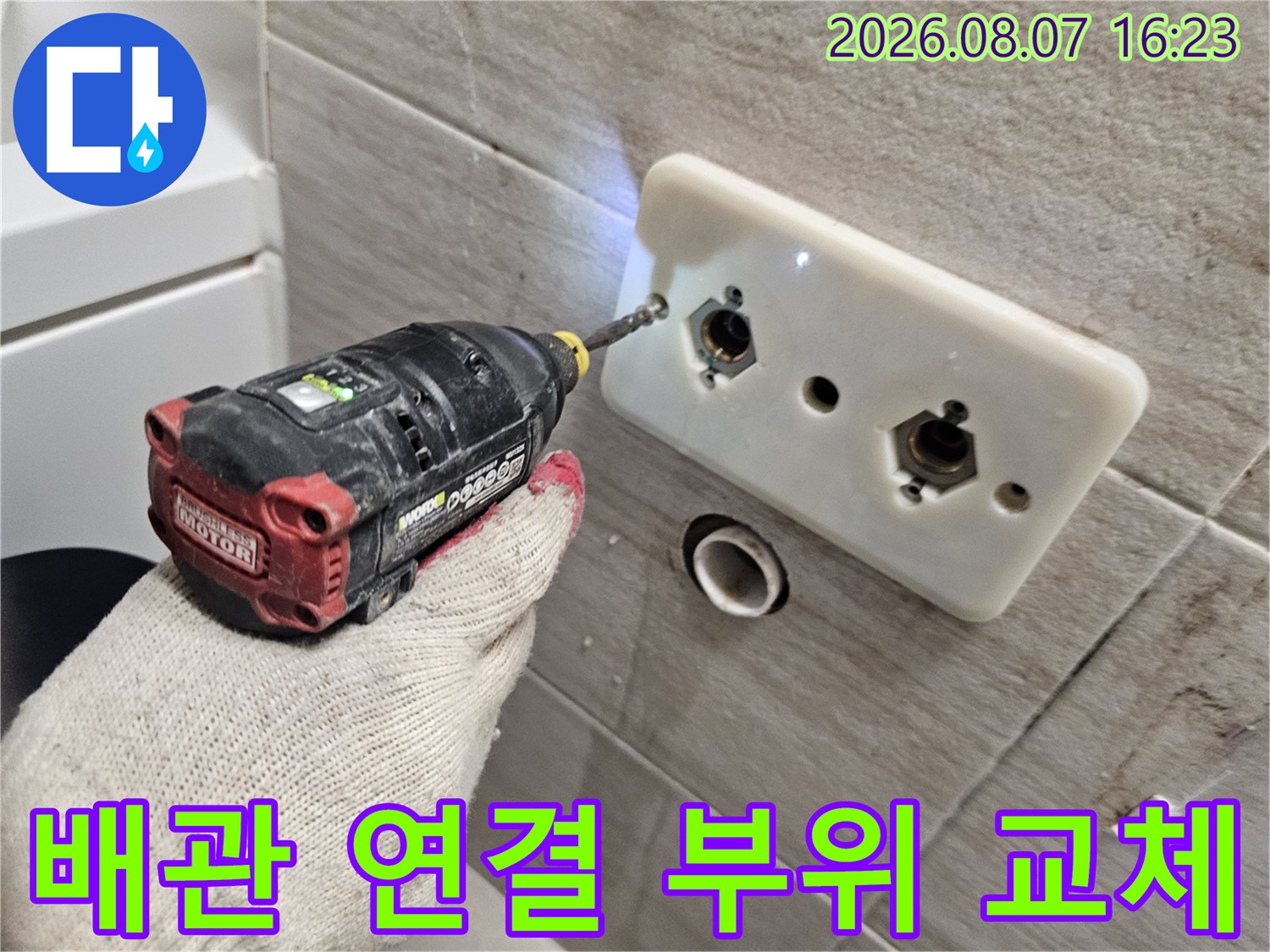 세면대 벽면 타일을 제거하고 노출된 배관 부속을 만지는 작업 장면입니다.