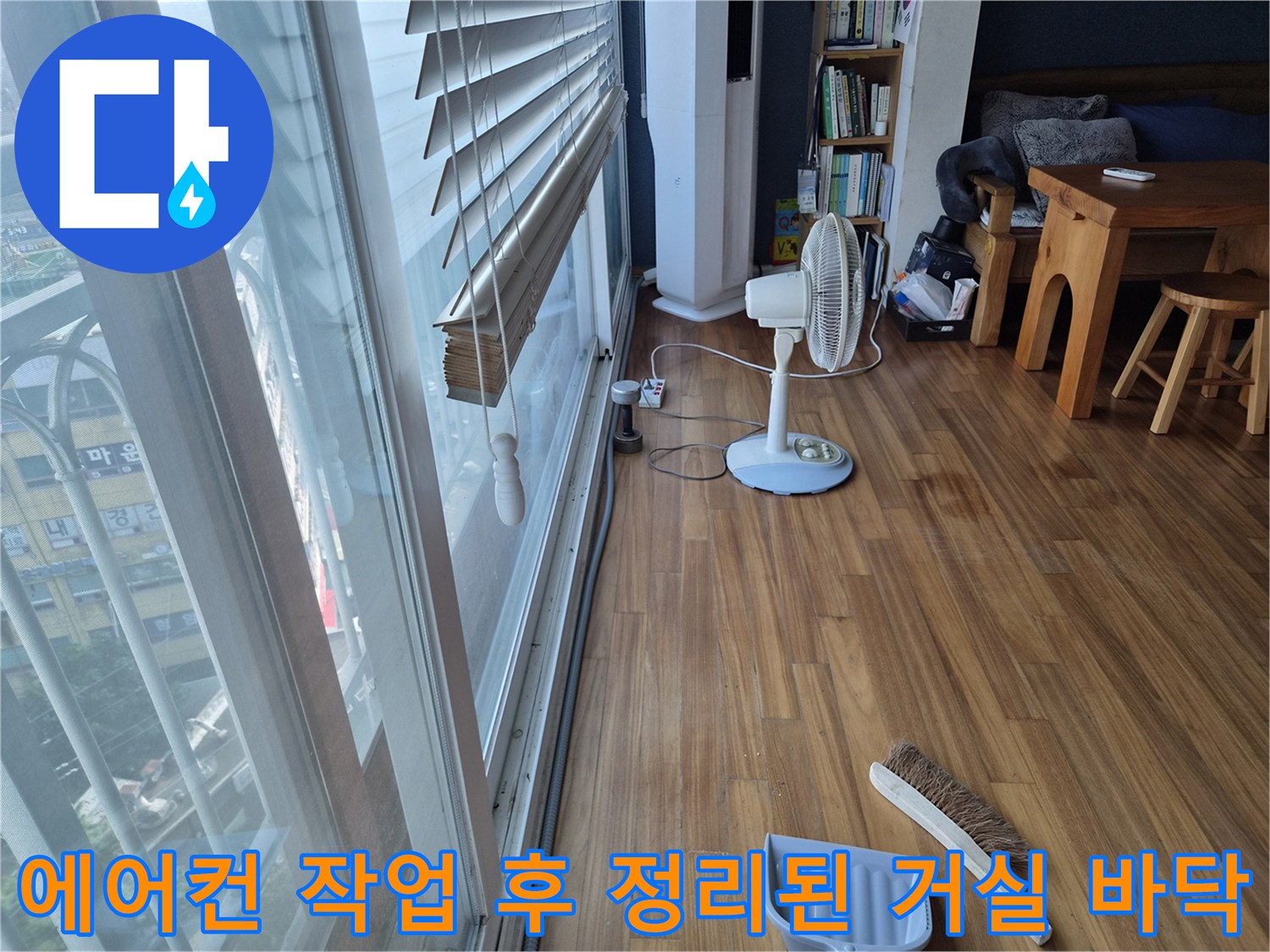 에어컨 누수 작업을 마친 후 깨끗하게 정리된 나무 바닥과 선풍기 모습입니다.
