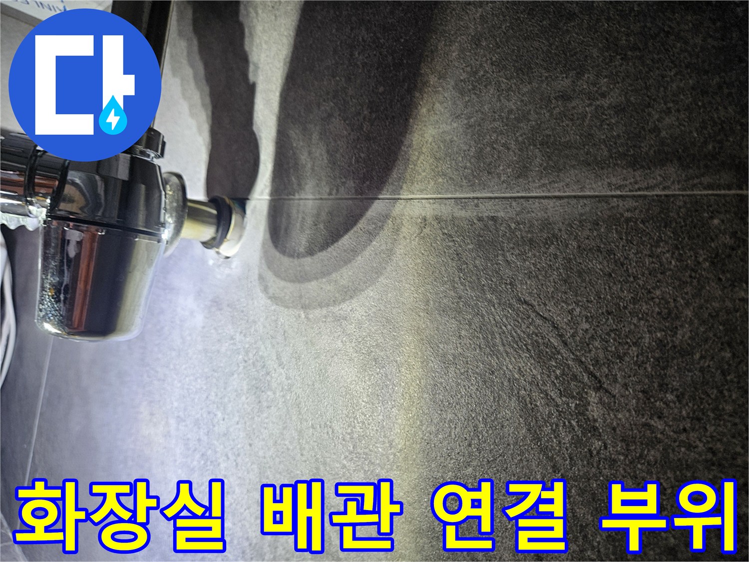 어두운 색 타일 벽면에 설치된 크롬 도금 배관 연결부 모습