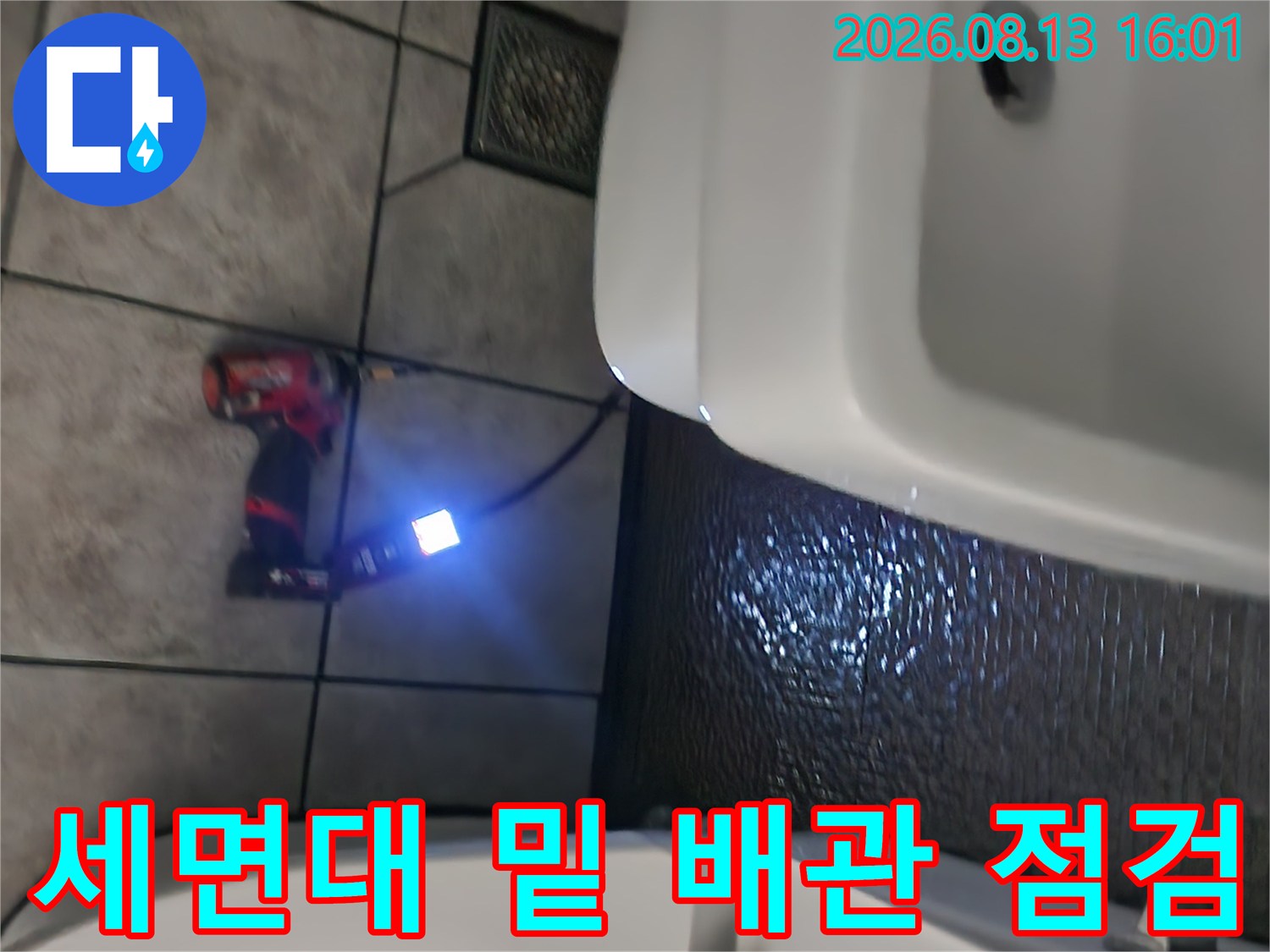 밝은 조명을 사용하여 세면대 하부의 어두운 배관 구석을 비추고 있습니다.