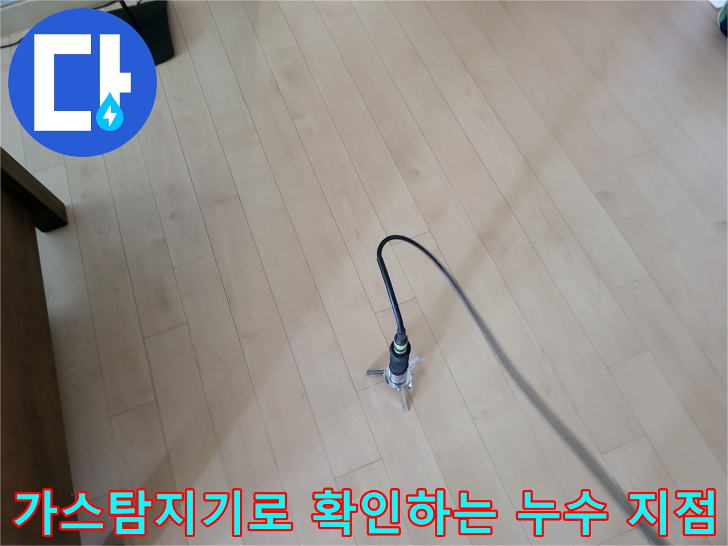 거실 마루 바닥 위에서 가스 탐지기를 활용하여 배관의 이상 유무를 정밀하게 체크하고 있습니다.