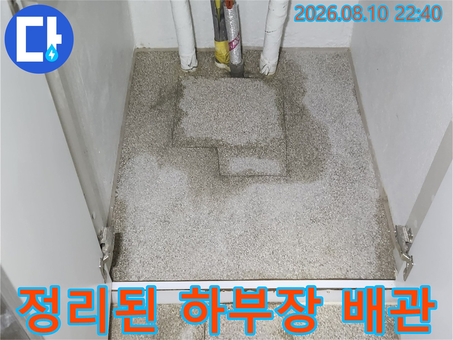 싱크대 아래쪽의 보온재가 입혀진 배관과 미장 마감된 바닥입니다.
