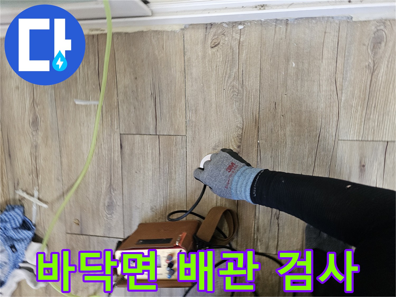 나무 무늬 마루 위에서 누수 측정기를 조작하는 손과 장비