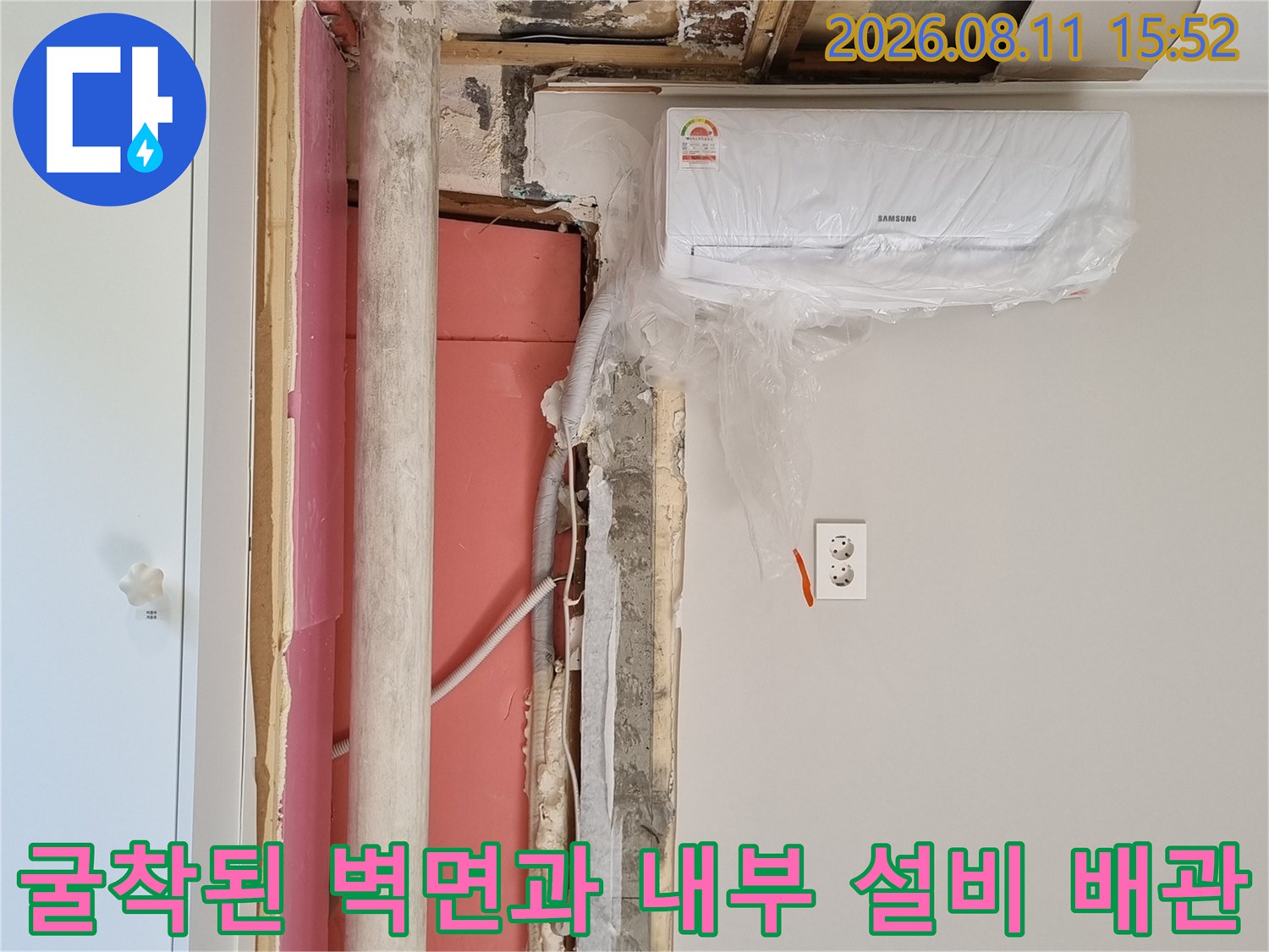 에어컨 하단 벽체가 제거되어 노출된 흰색 배관과 분홍색 단열재의 모습