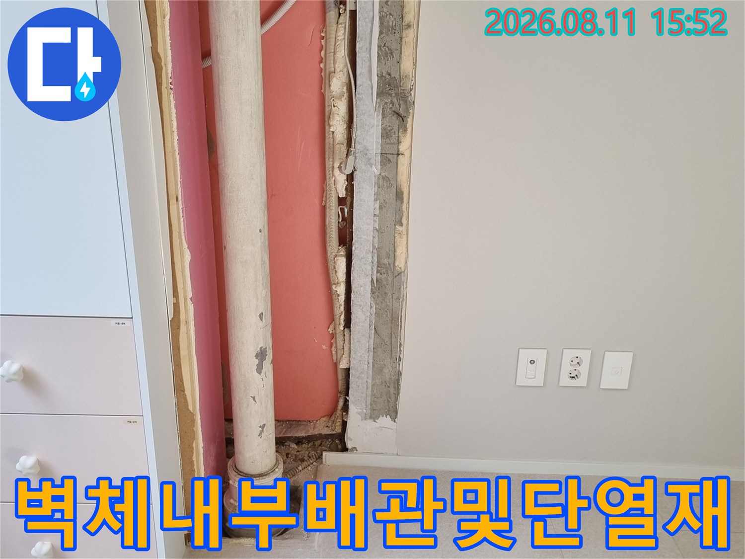 흰색 콘센트 아래로 벽체가 굴착되어 내부 우수관과 단열재가 드러난 사진