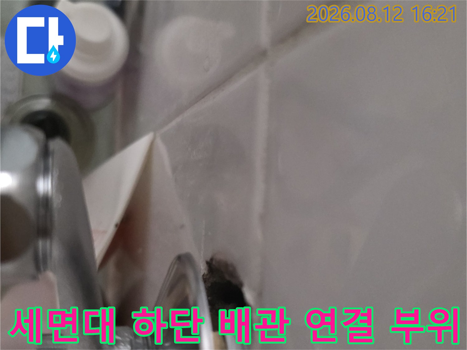 욕실 세면대 아래쪽으로 설치된 금속제 배관과 타일 접합부-누수 점검 모습