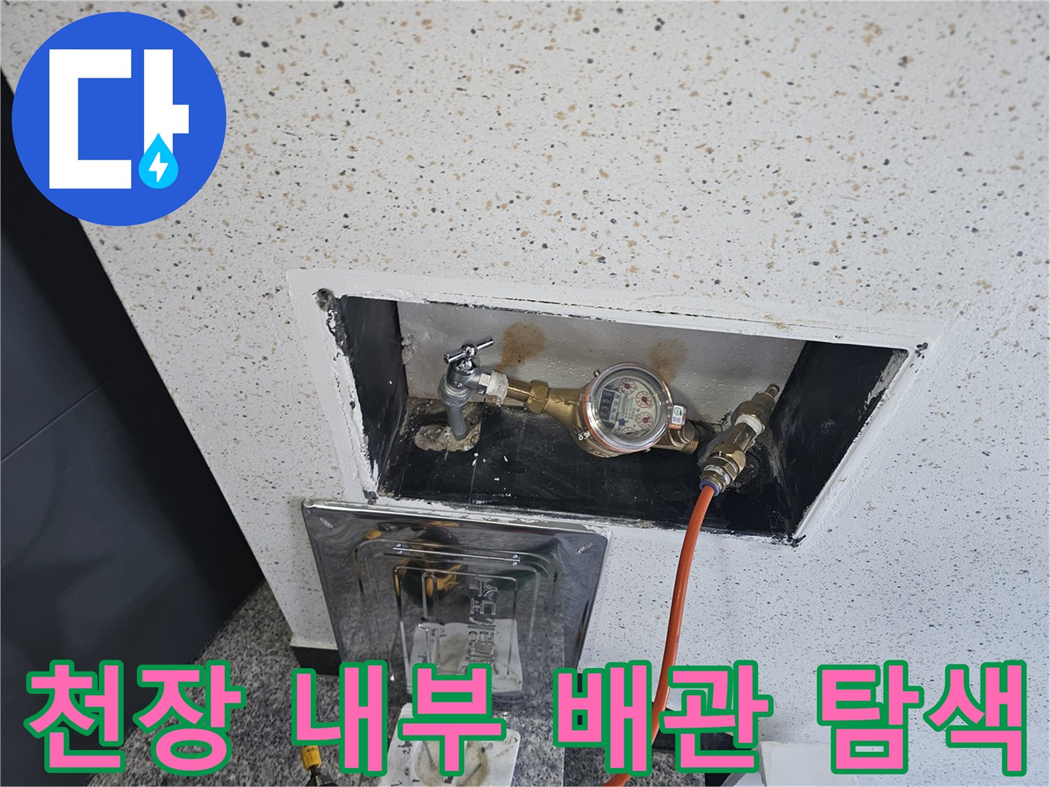 점검구 내부에 노출된 수도 배관과 계량기를 촬영한 사진입니다.