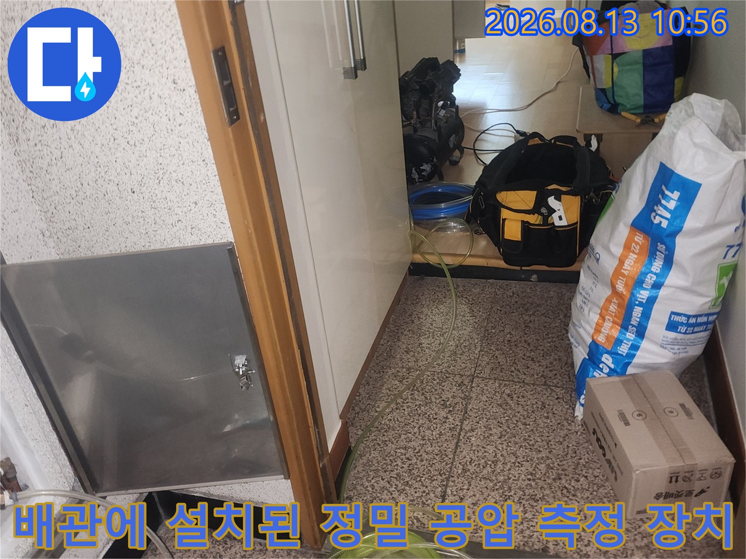금속 점검구 덮개 주변으로 노란색 호스와 압력 계측기가 연결되어 배치된 현장 사진