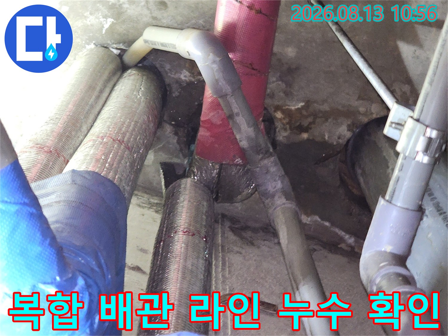 회색과 분홍색의 서로 다른 재질의 배관들이 천장 공간에 배치된 현장 사진