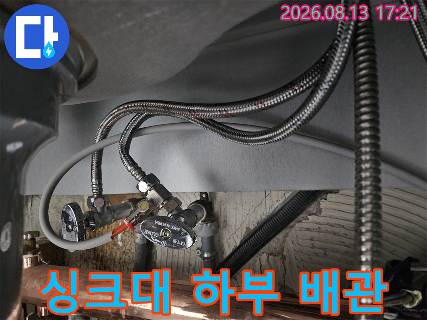 싱크대 아래쪽 앵글밸브와 연결된 금속 호스의 클로즈업 사진입니다.