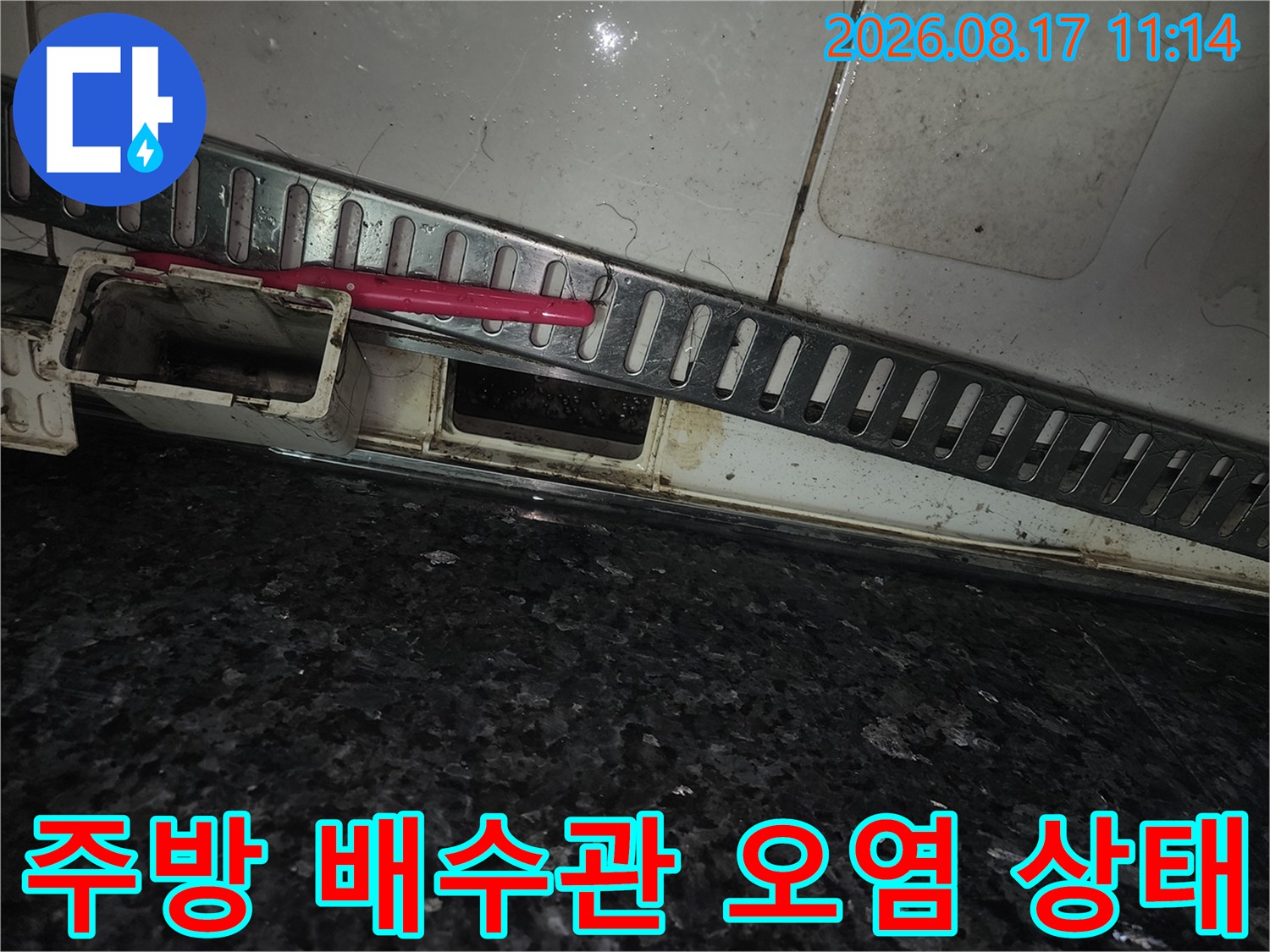 싱크대 하단 타일 부위-배수관 주변의 젖은 흔적과 오염된 모습을 보여줍니다.