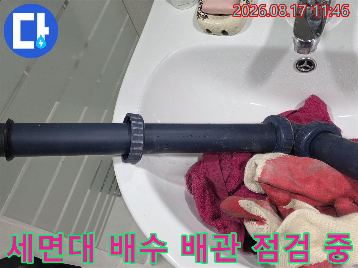 세면대 하단 어두운색 배수 배관과 주변 작업 도구 사진입니다