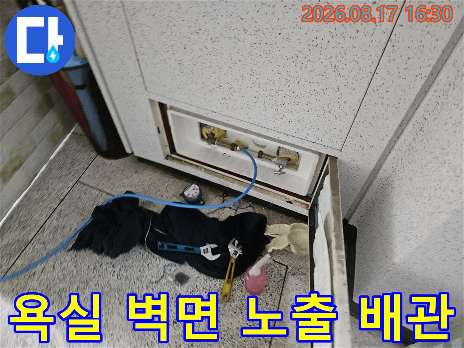 타일 안쪽으로 드러난 수도 배관과 작업용 도구들