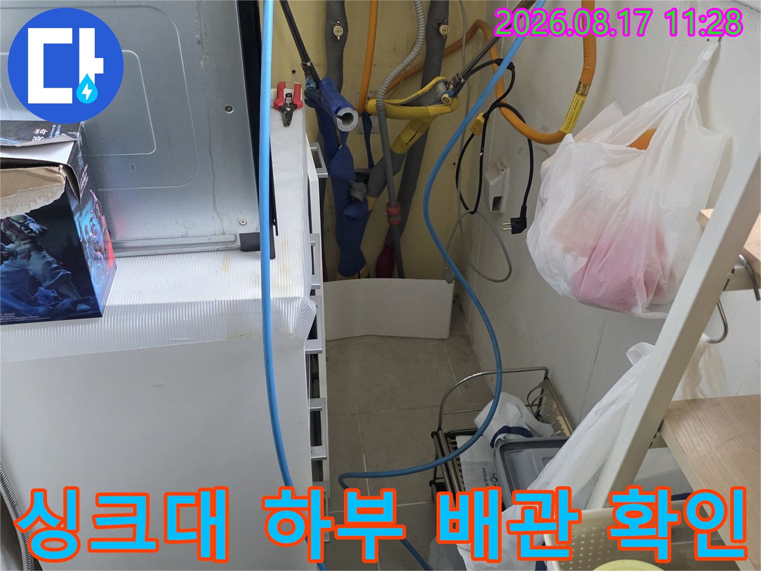 싱크대 아래쪽 정수기 호스와 급수 배관들이 복잡하게 얽힌 모습