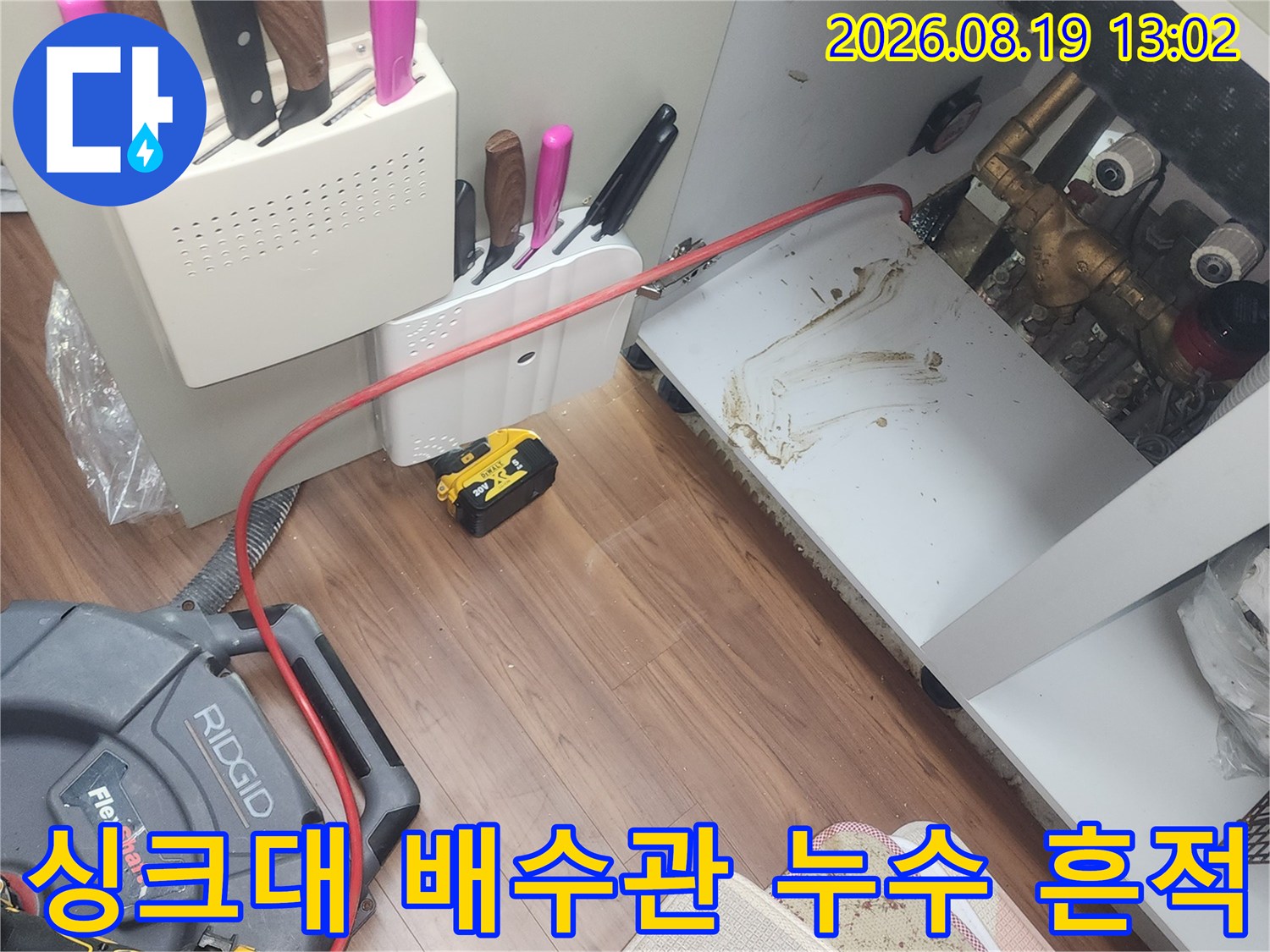 싱크대 하단 배관 주변의 누수 자국과 작업용 샤프트 장비 모습