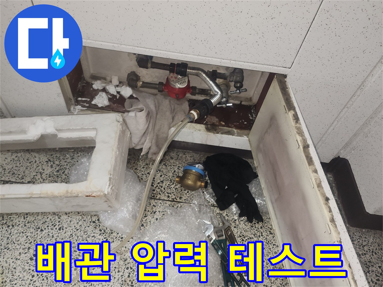 싱크대 하부장 내부-배관 연결 부위에 장비를 설치하여 공압 검사를 수행 중입니다