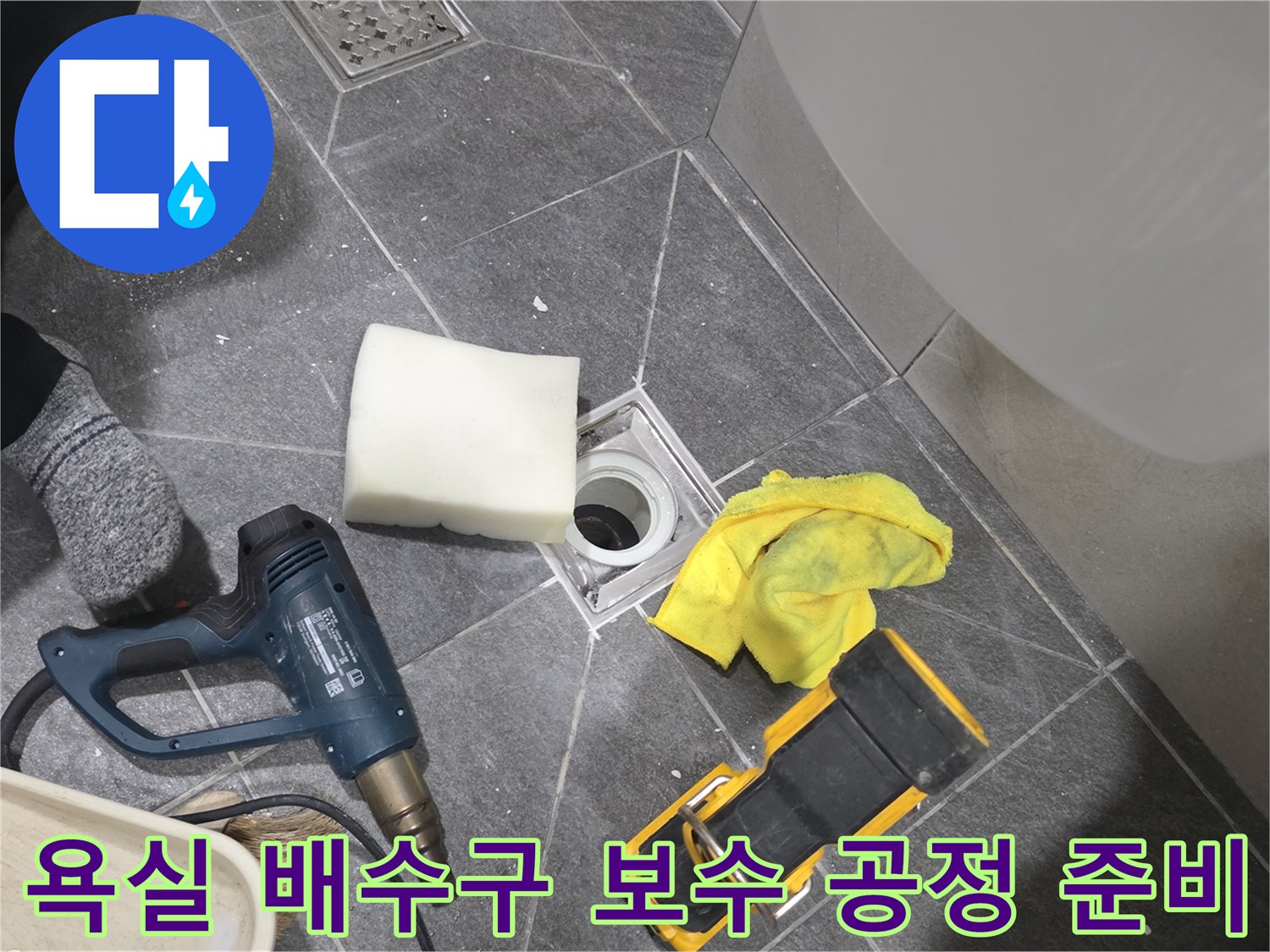 작업을 위해 드릴과 청소 도구가 배치된 욕실 바닥 배수구 근처입니다.