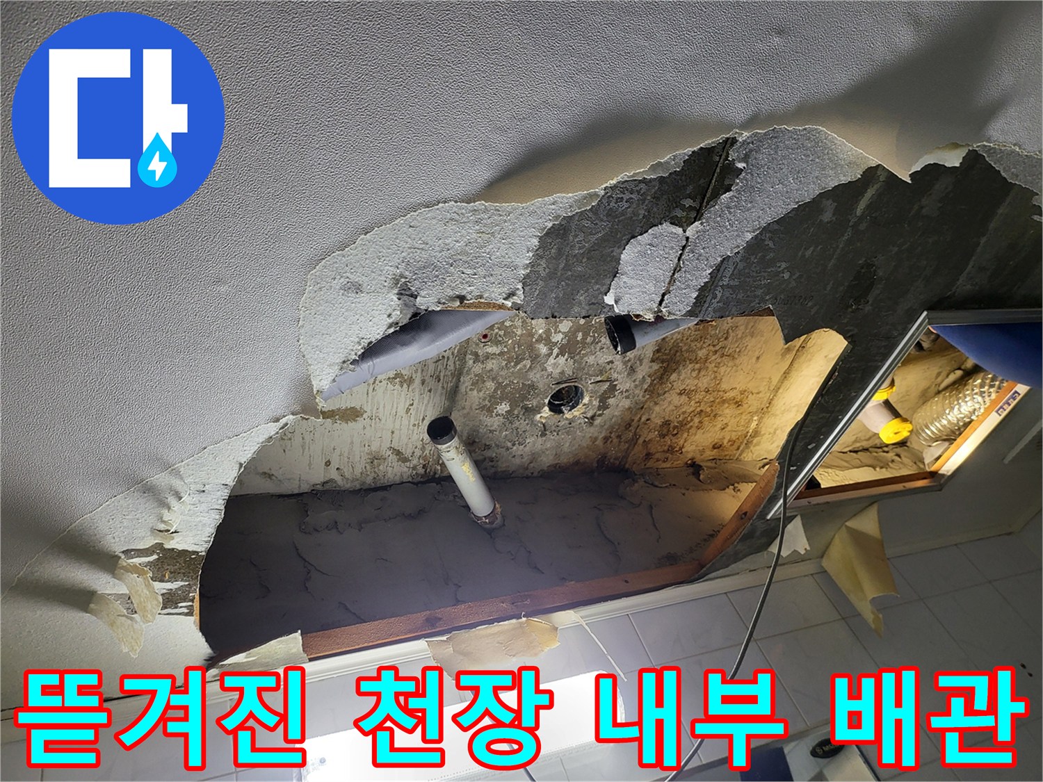 욕실 천장 마감재가 찢겨져 있고 흰색 배관이 보이는 모습
