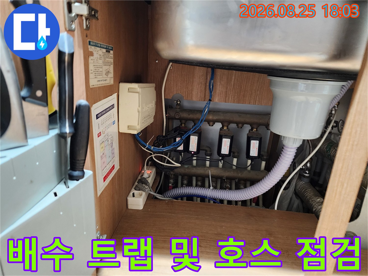 싱크대 하단 배수 트랩과 굴곡진 배수 호스의 연결 상태를 촬영한 사진입니다.