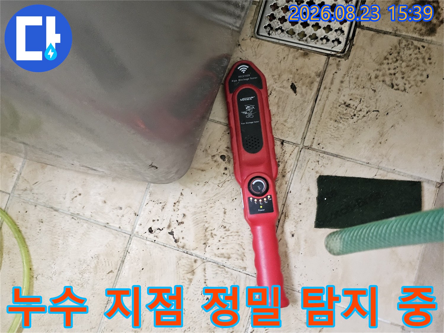 붉은색 가스 탐지기를 바닥 타일 근처에 대고 배관의 누수 여부를 면밀히 검사하고 있습니다.