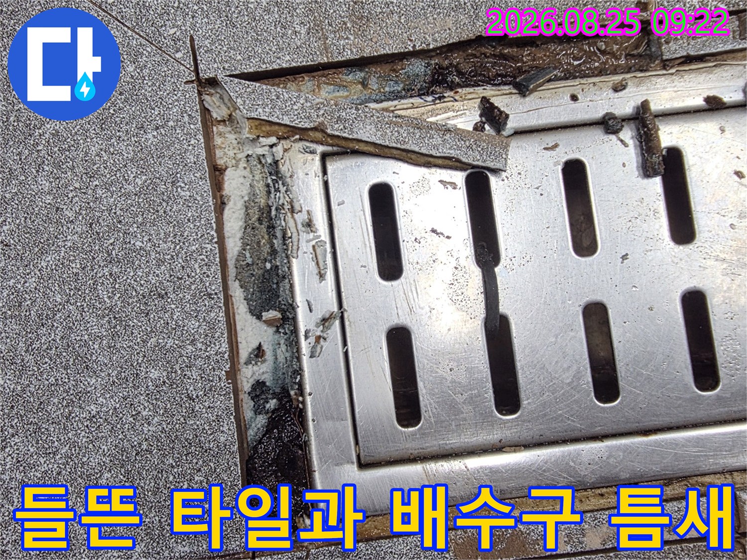 배수구 주변의 벌어진 타일 틈새와 노출된 하부 구조물