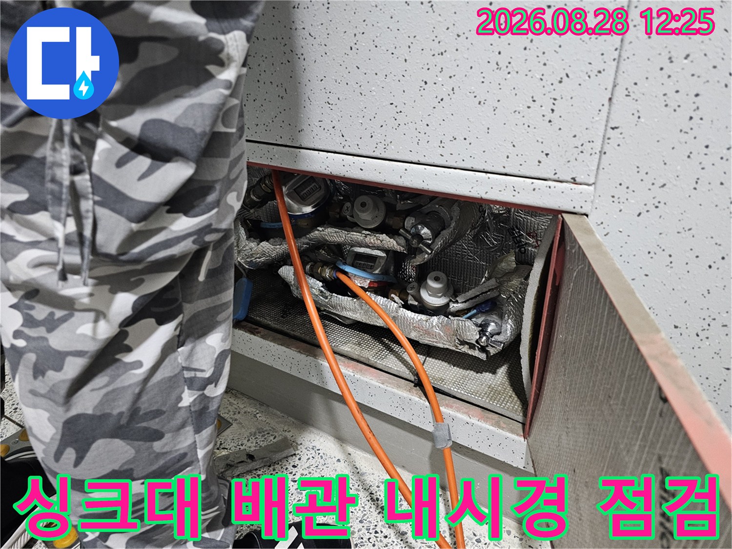 싱크대 하단 공간에 배치된 배관들과 검사를 위해 투입된 장비를 촬영한 사진입니다.