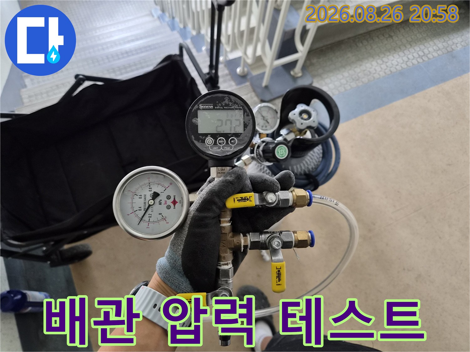 공압 장비를 배관 연결 부위에 설치하여 압력을 측정하고 있습니다.