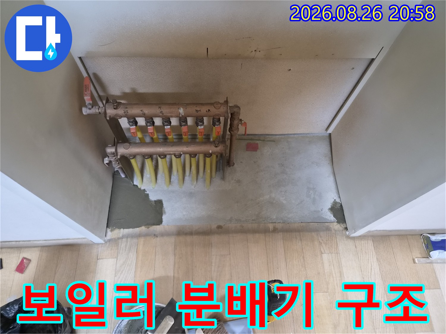 벽면 안쪽 공간에 설치된 보일러 분배기와 연결 배관의 모습입니다.