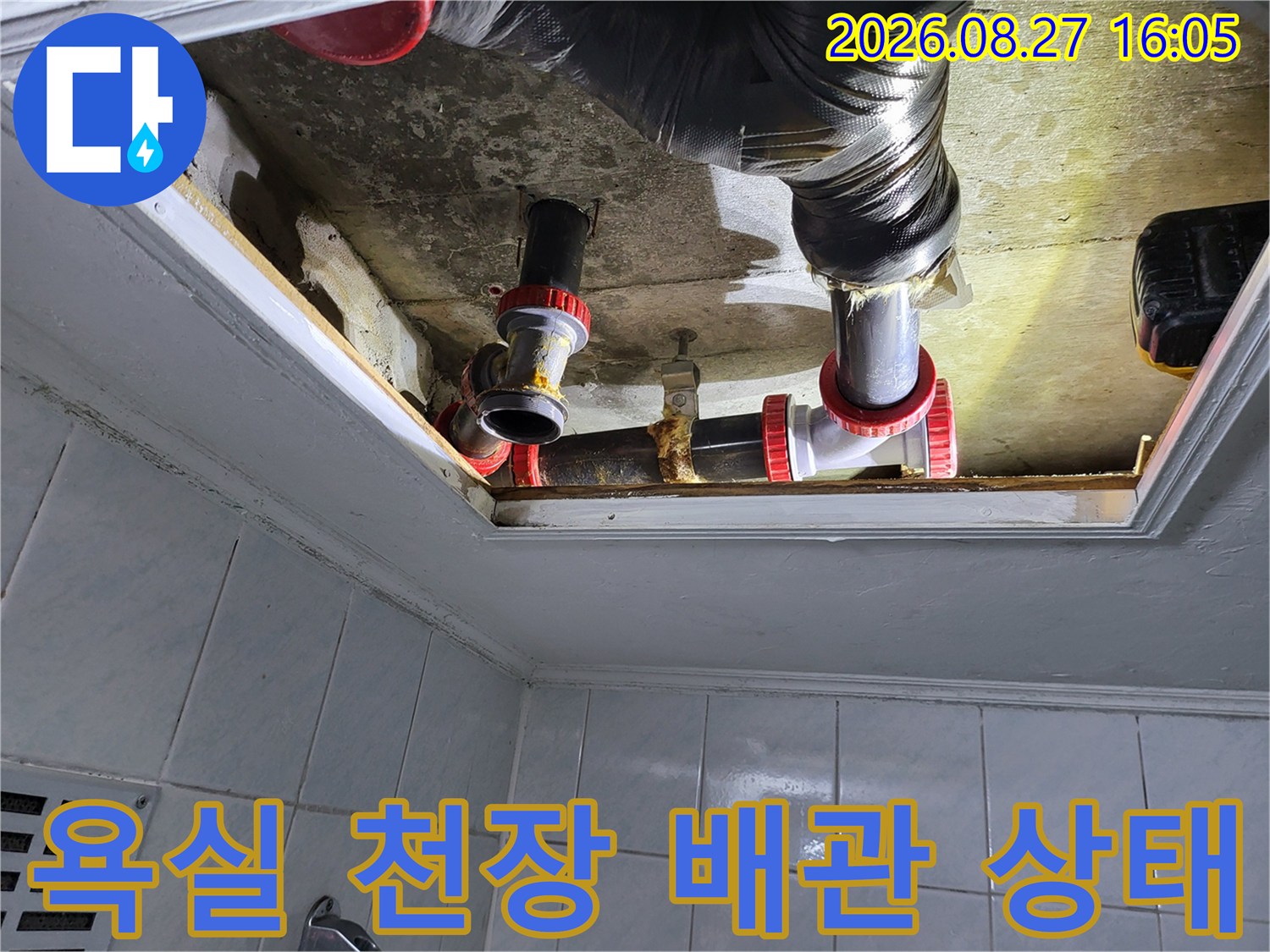 점검구 내부의 검은색 주름관과 은색 배관이 연결된 화장실 천장 누수 보수 완료 모습입니다.