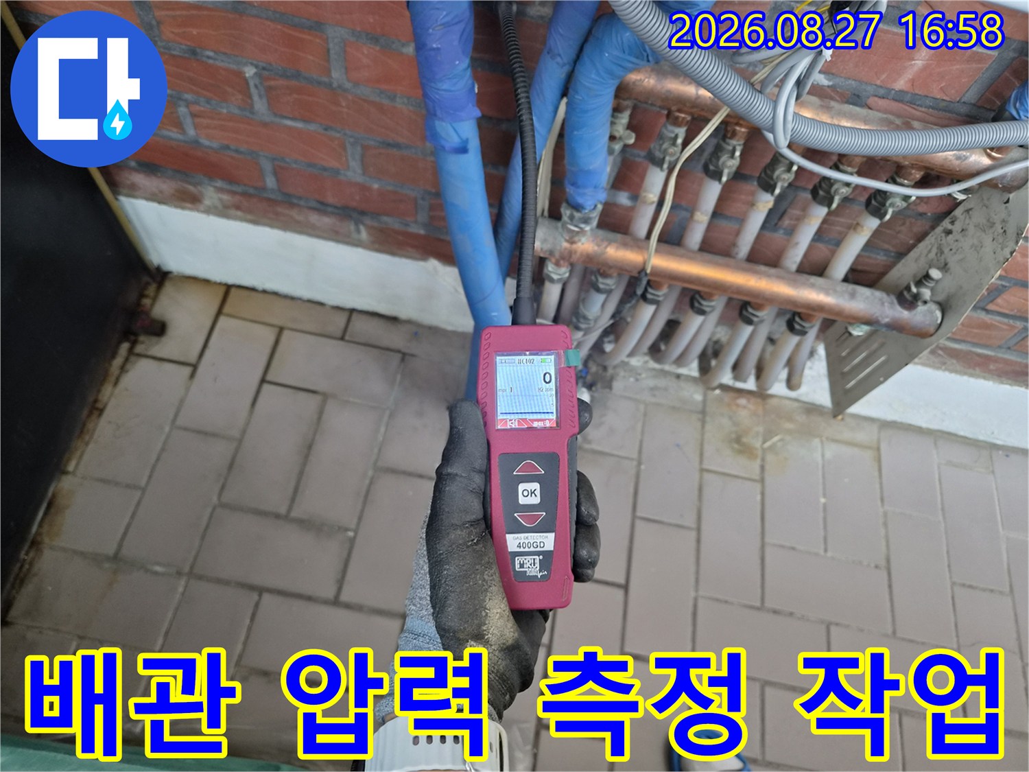 보온재로 감싸진 배관과 구리 관 사이에-압력계를 연결하여 누수 여부를 확인하는 중입니다.