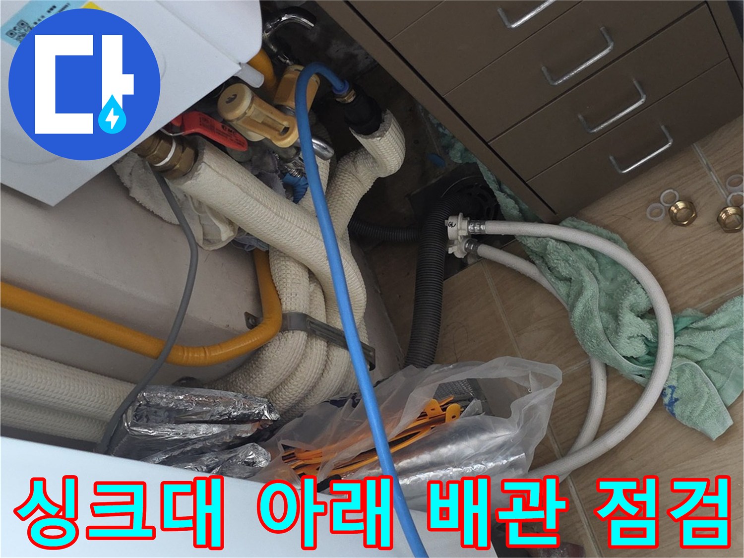 민락동 아파트 싱크대 하부장 내 노란색 배관과 흰색 호스 근접 촬영