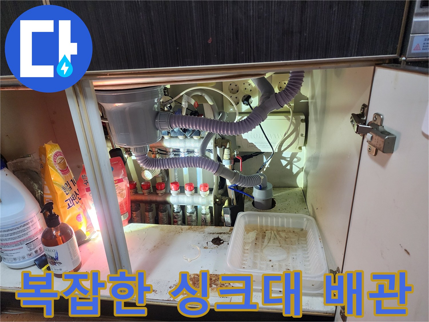 싱크대 하부의 에어컨 드레인 호스와 연결된 여러 배관들