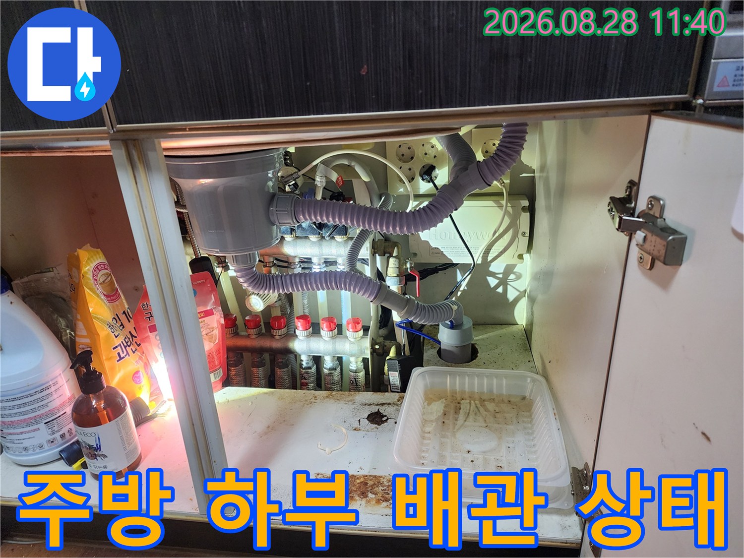 싱크대 하부장 내부에 복잡하게 연결된 정수 필터와 호스들