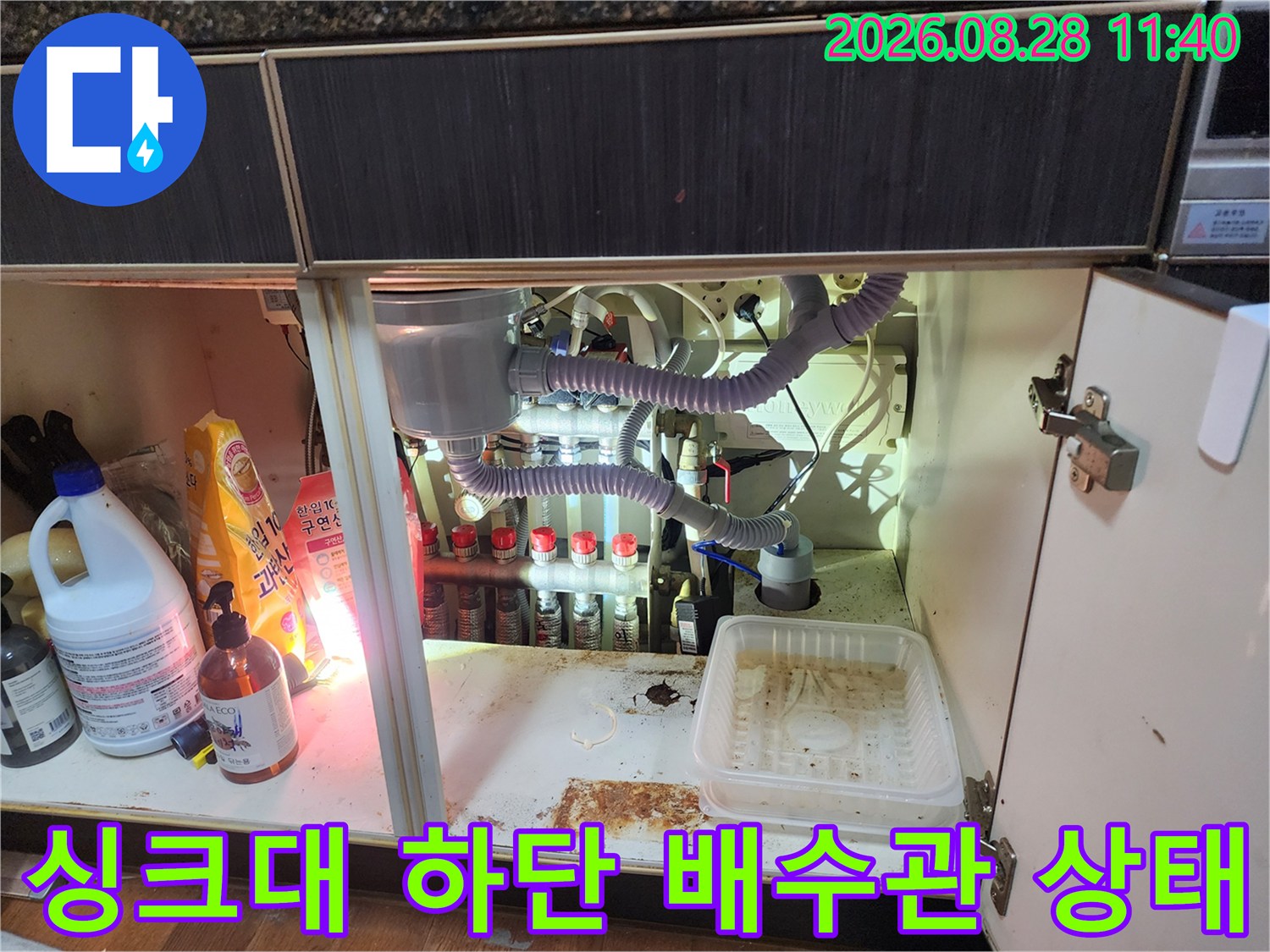 싱크대 하부장 내부의 복잡한 배수 호스 및 연결 부위 모습