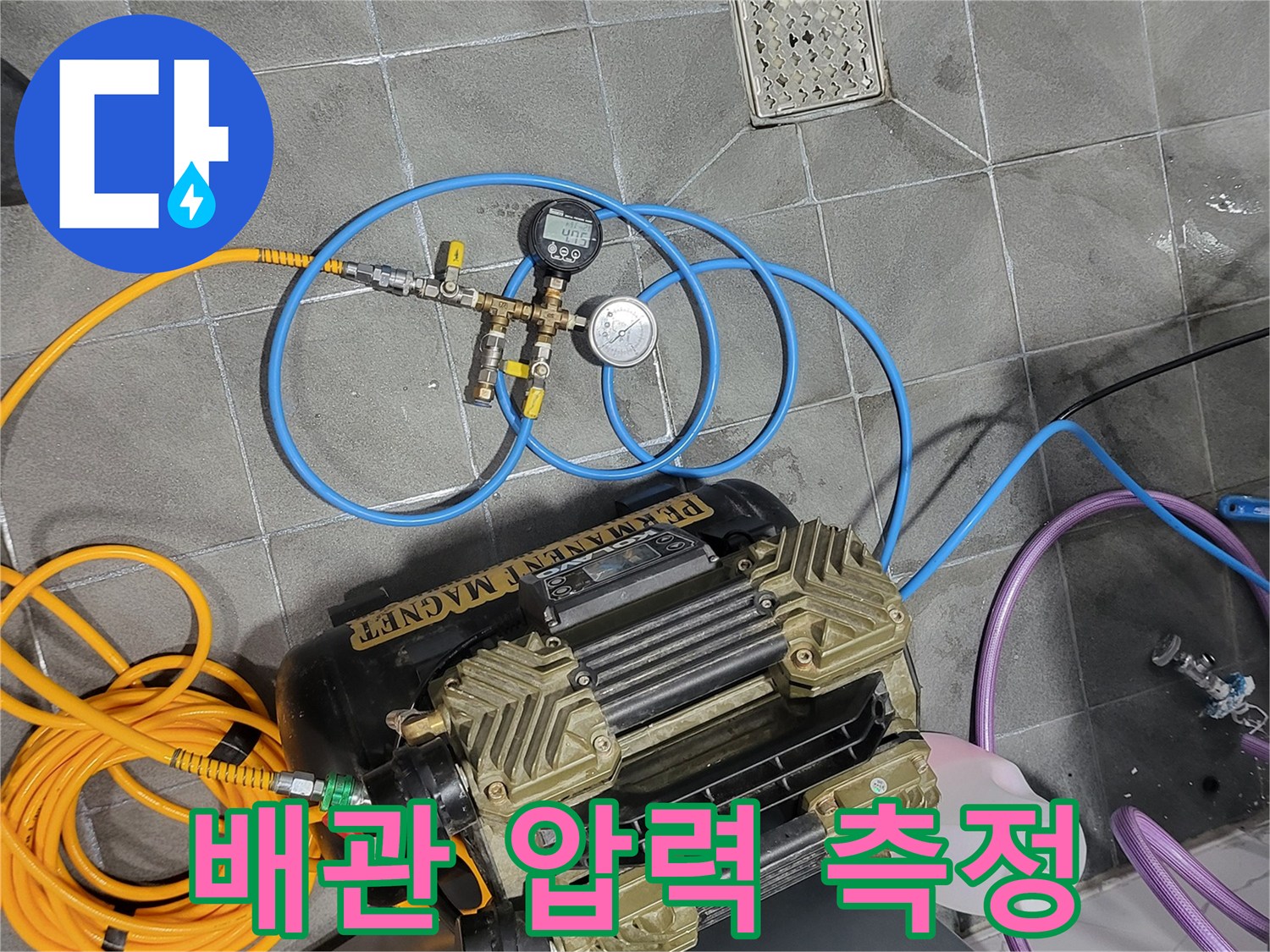 바닥 타일 위에 설치된 공압 테스트용 게이지와 호스 연결