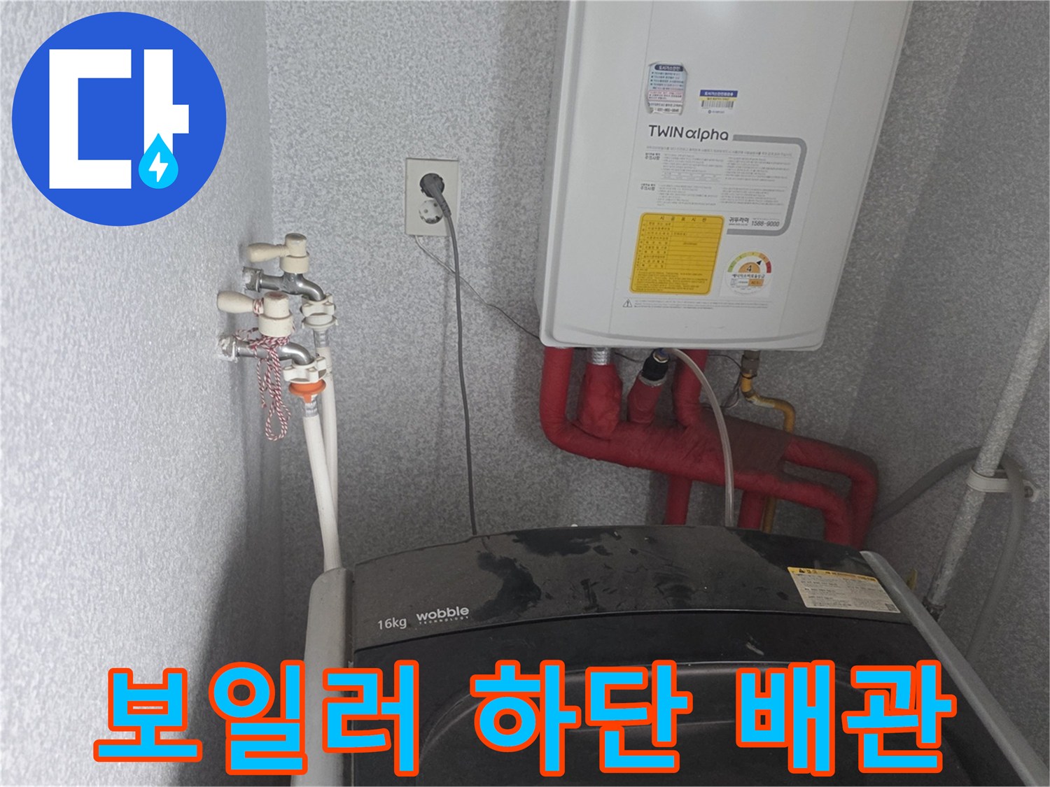 보일러 하부 연결된 붉은색 배관과 벽면 수전의 근접 촬영