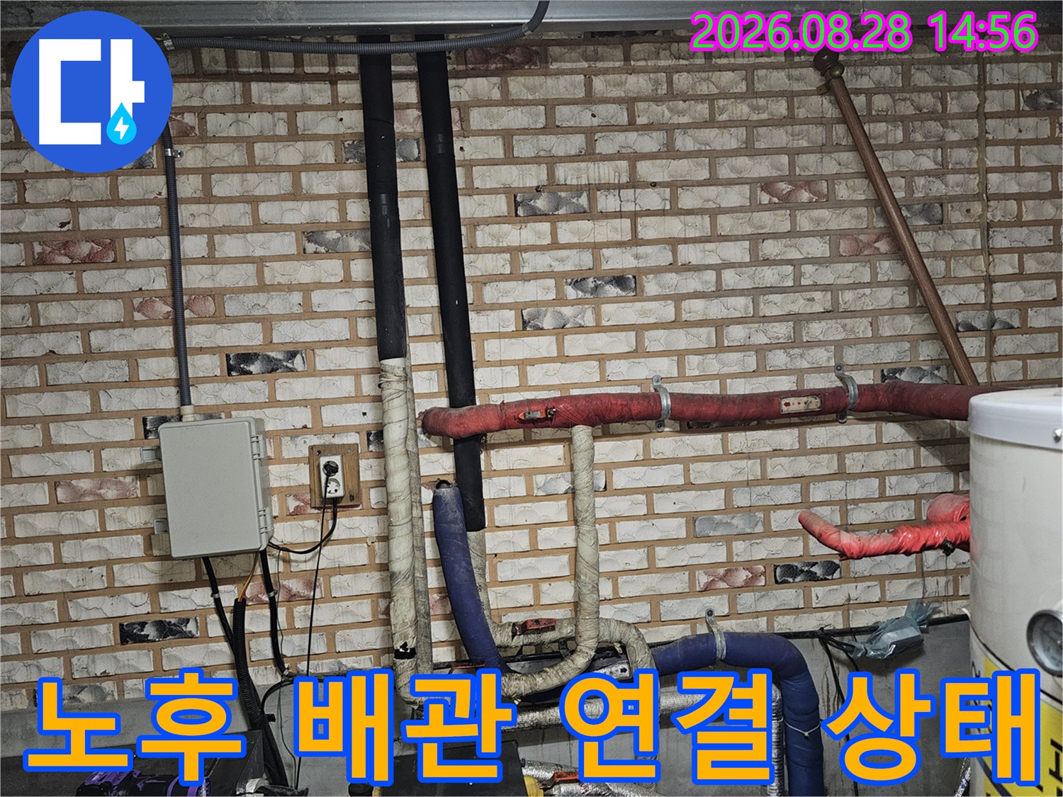 보온재가 씌워진 배관들과 벽돌 벽면의 연결 부위 사진입니다.