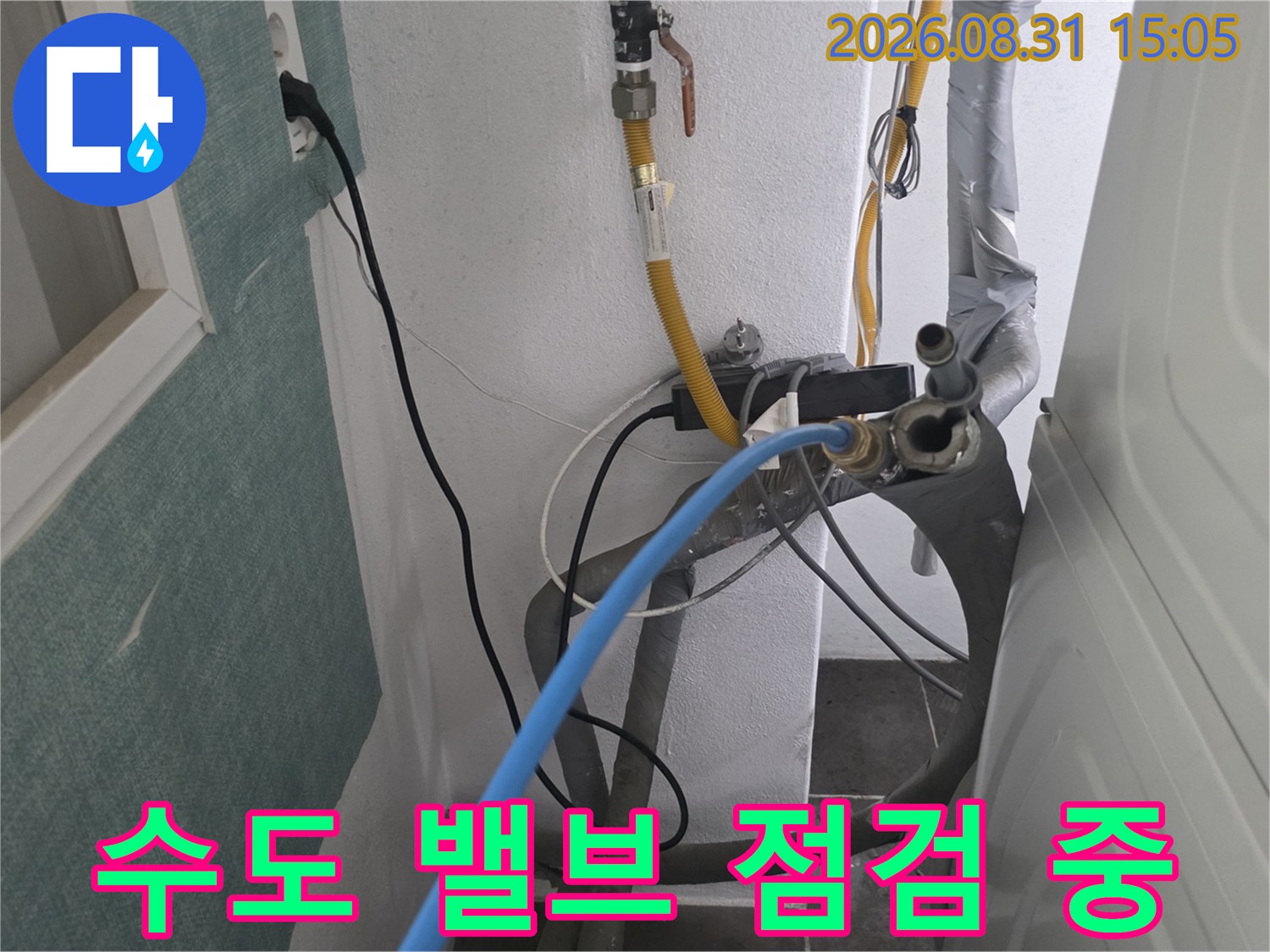 벽체에 연결된 수전 밸브와 압력 테스트용 파란색 호스 모습
