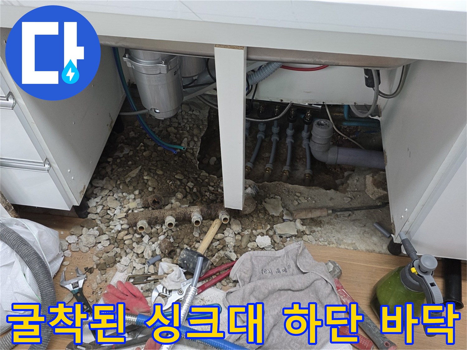 싱크대 아래쪽-파헤쳐진 흙과 자갈 및 노출된 배관