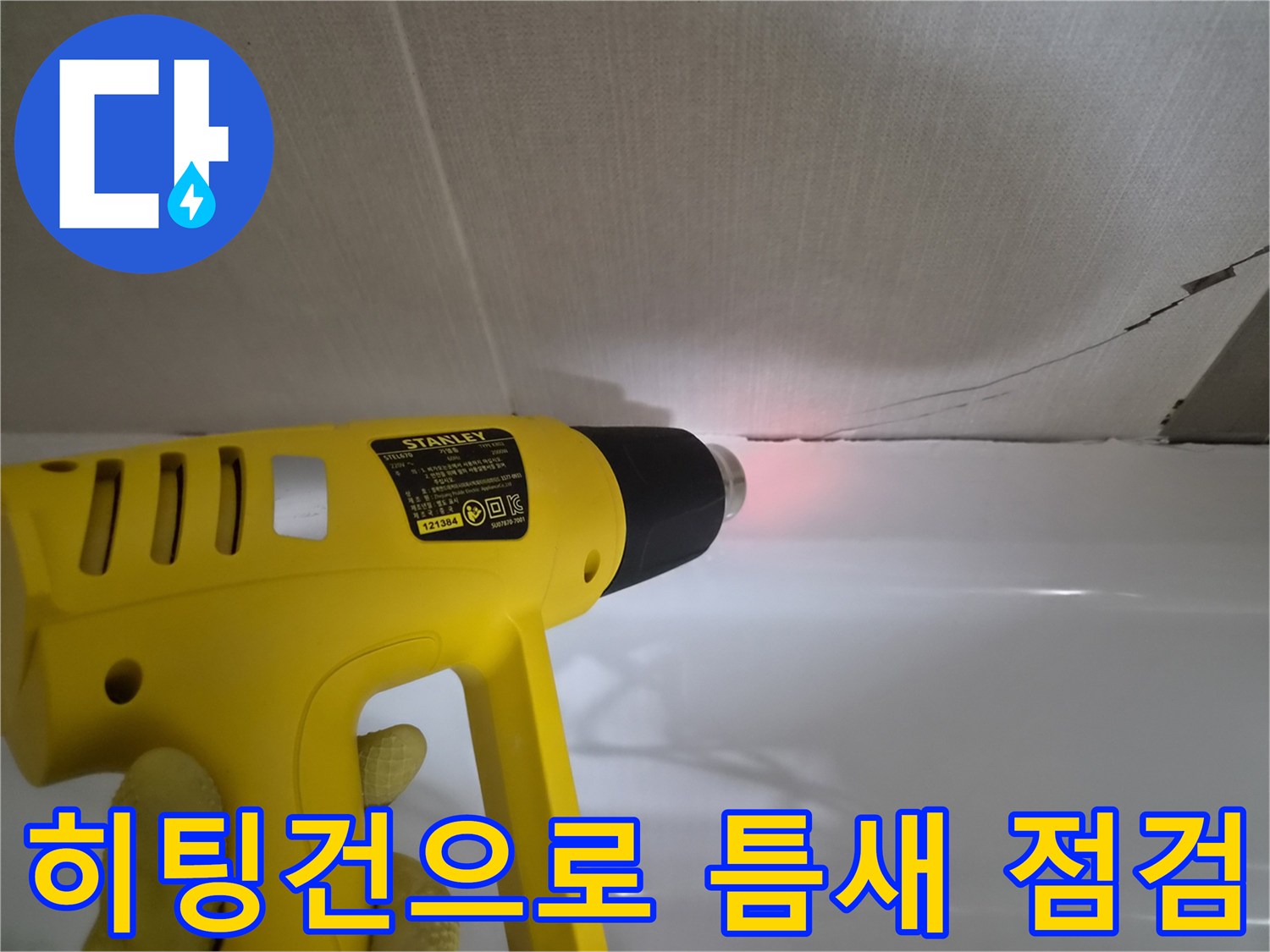 히팅건을 사용하여-욕조와 벽면 사이의 균열 부위를 정밀하게 살피는 모습