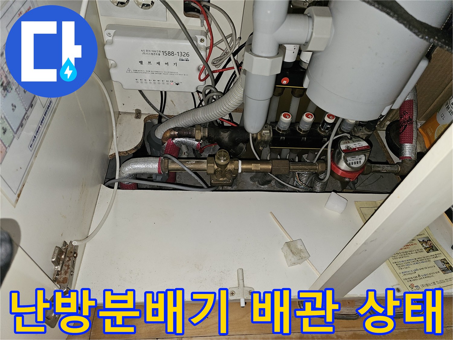 분당 백현동 아파트 주방 하부장 내부의 노후된 난방 배관과 분배기 모습