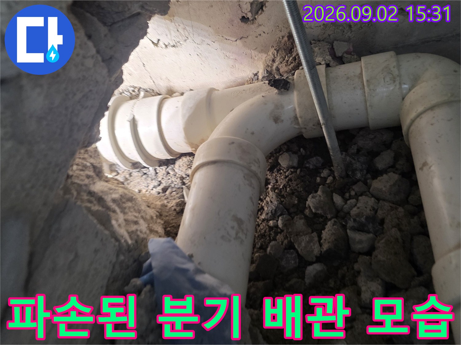 흙과 자갈 사이로 드러난-손상된 화장실 배관입니다.