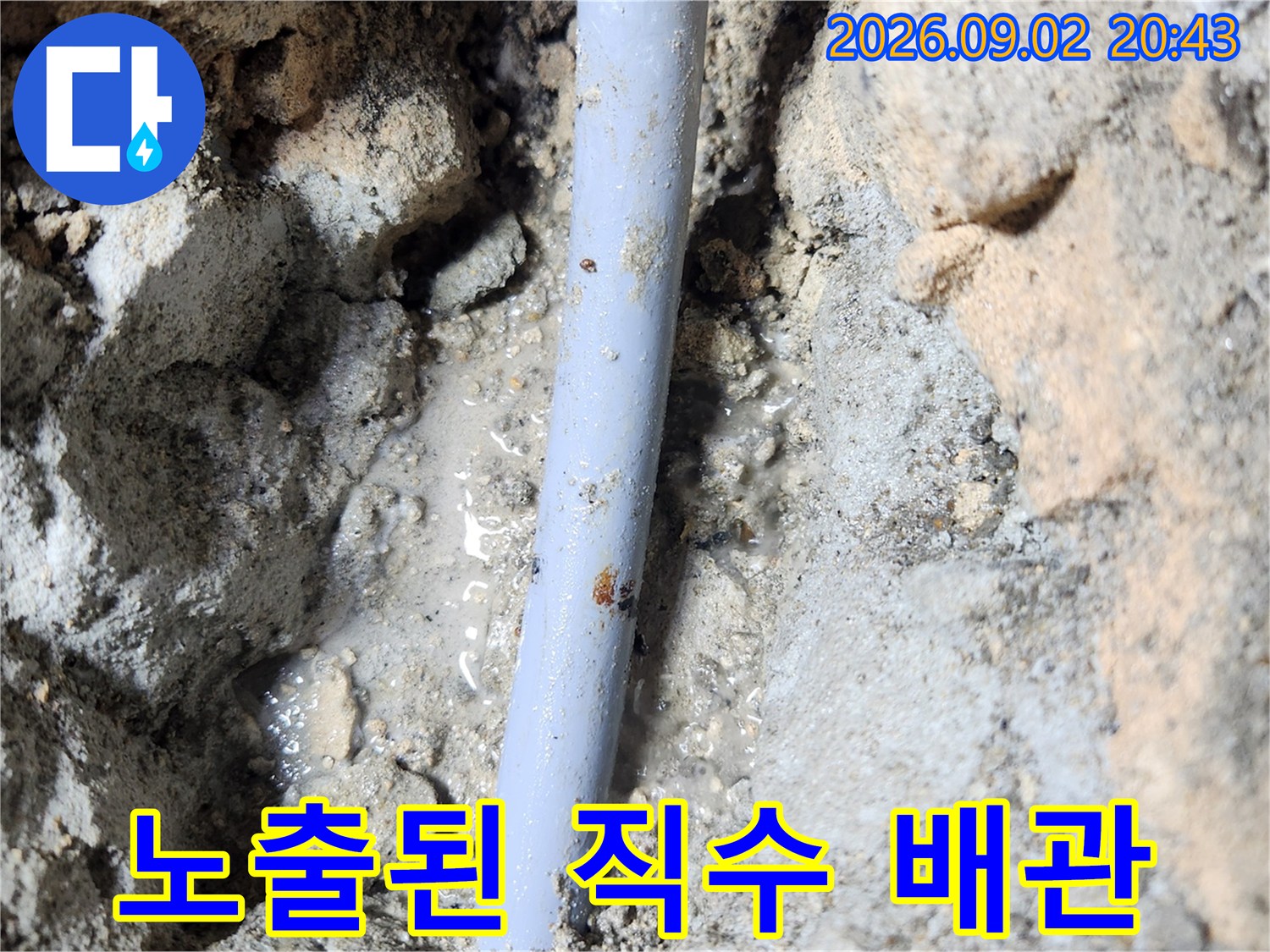 바닥을 파낸 뒤 드러난 하얀색 직수 배관과 젖은 흙의 모습입니다.