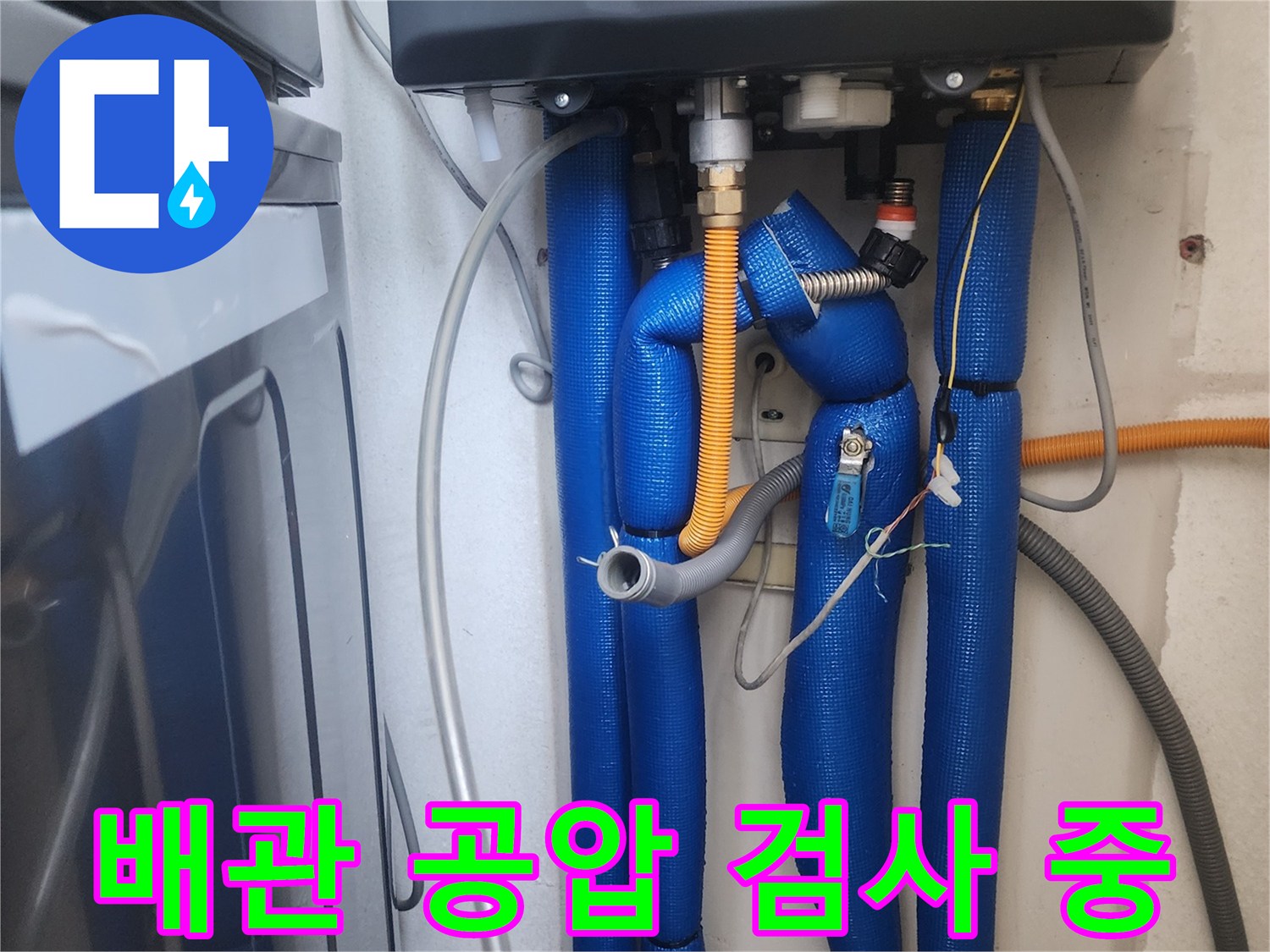 파란색 보온재로 감싸진 배관에 공압 장비를 연결하여 누수 여부를 확인하는 모습입니다.