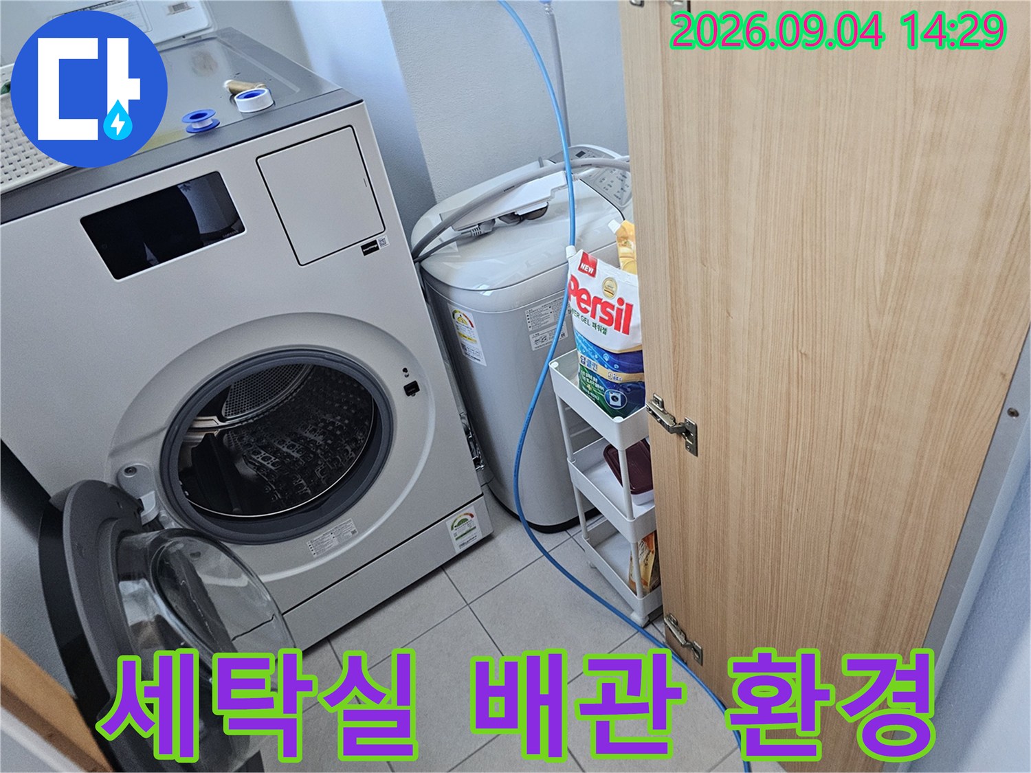 세탁기 뒤편의 세탁실 공간과 배관 위치를 보여주는 사진입니다.