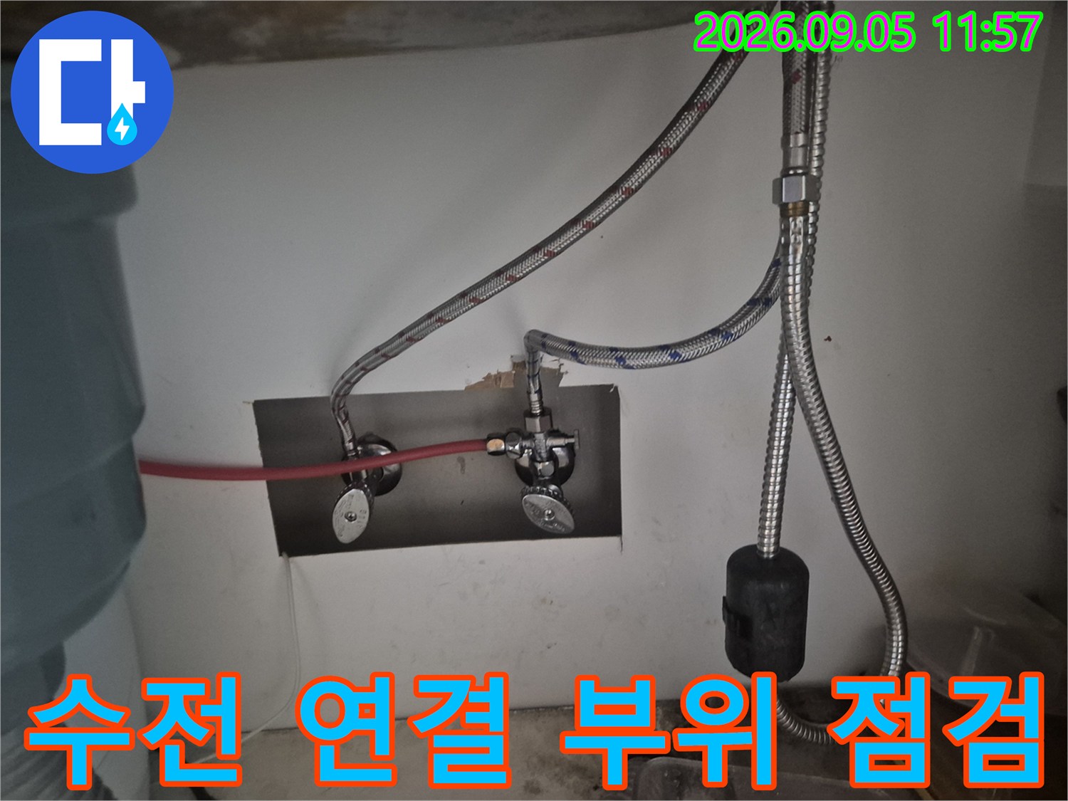싱크대 하부 벽면 밸브와 은색 수전 호스 설치 모습