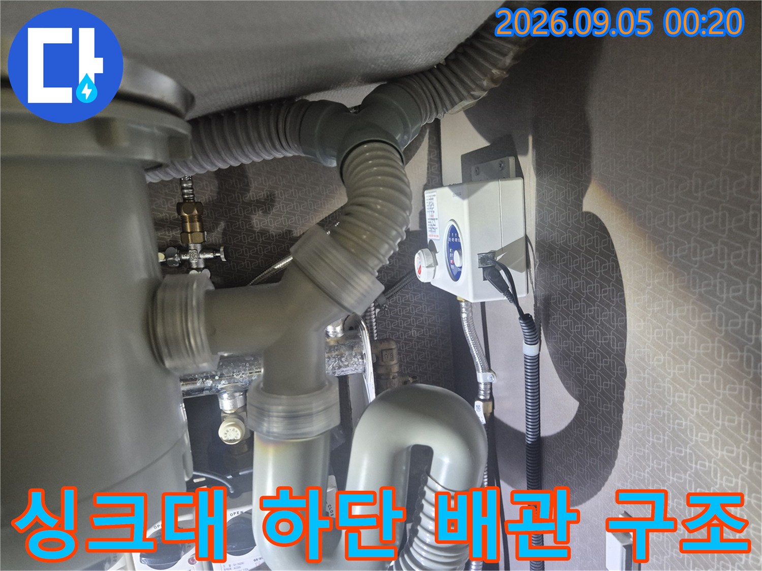 싱크대 하부의 굵은 배수 호스와 연결된 급수 부품 상세 사진