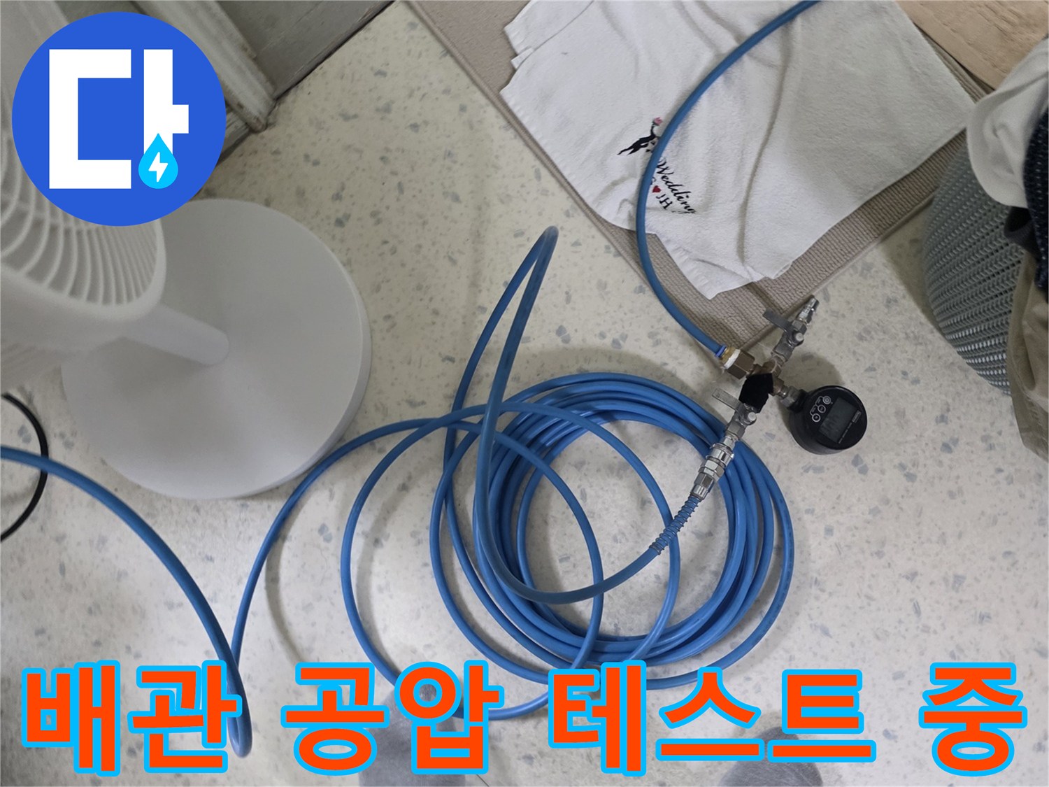 파란색 고압 호스와 압력계로 배관의 기밀 상태를 점기하는 모습입니다.