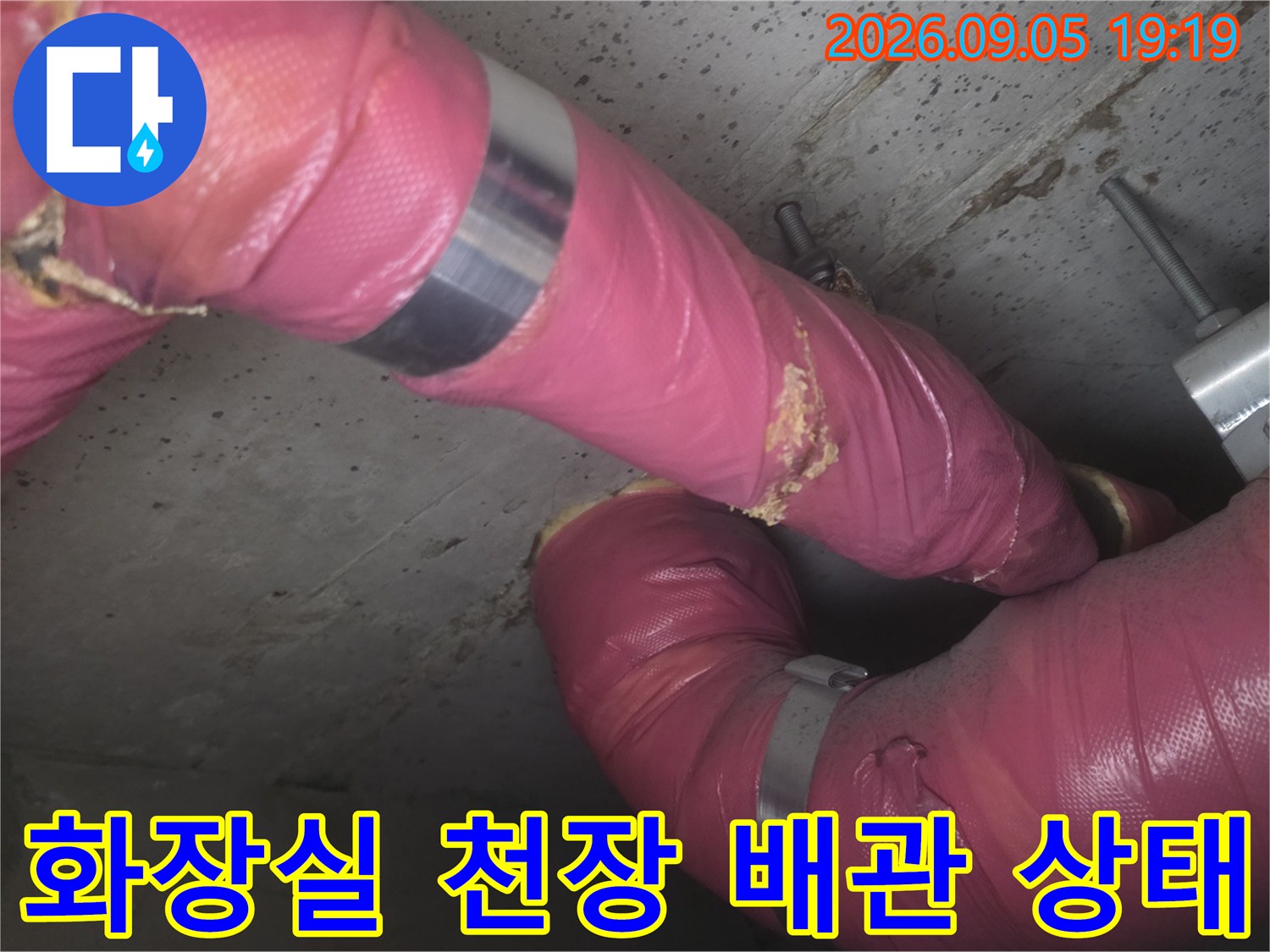 분홍색 보온재가 씌워진-배관의 연결 부위와 외부 노출 상태를 촬영한 사진입니다.